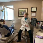 Denstist showing a patient something on a screen sitting in a dental chair at Tonka Smiles [CITY] [STATE]
