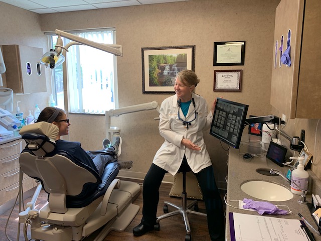 Denstist showing a patient something on a screen sitting in a dental chair at Tonka Smiles [CITY] [STATE]