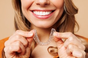 Woman holding Invisalign clear aligners